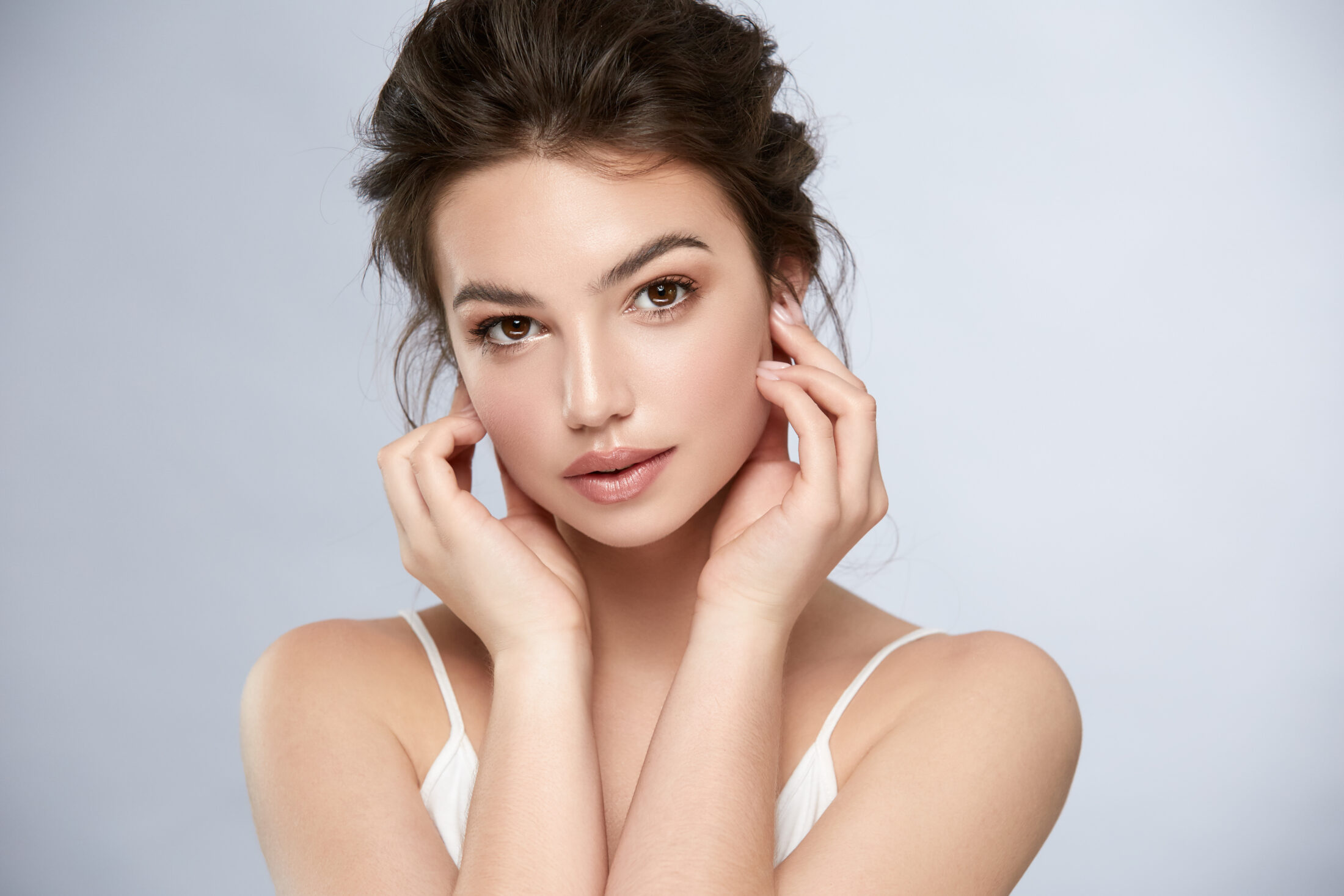 A beautiful brunette woman touching her face with both hands